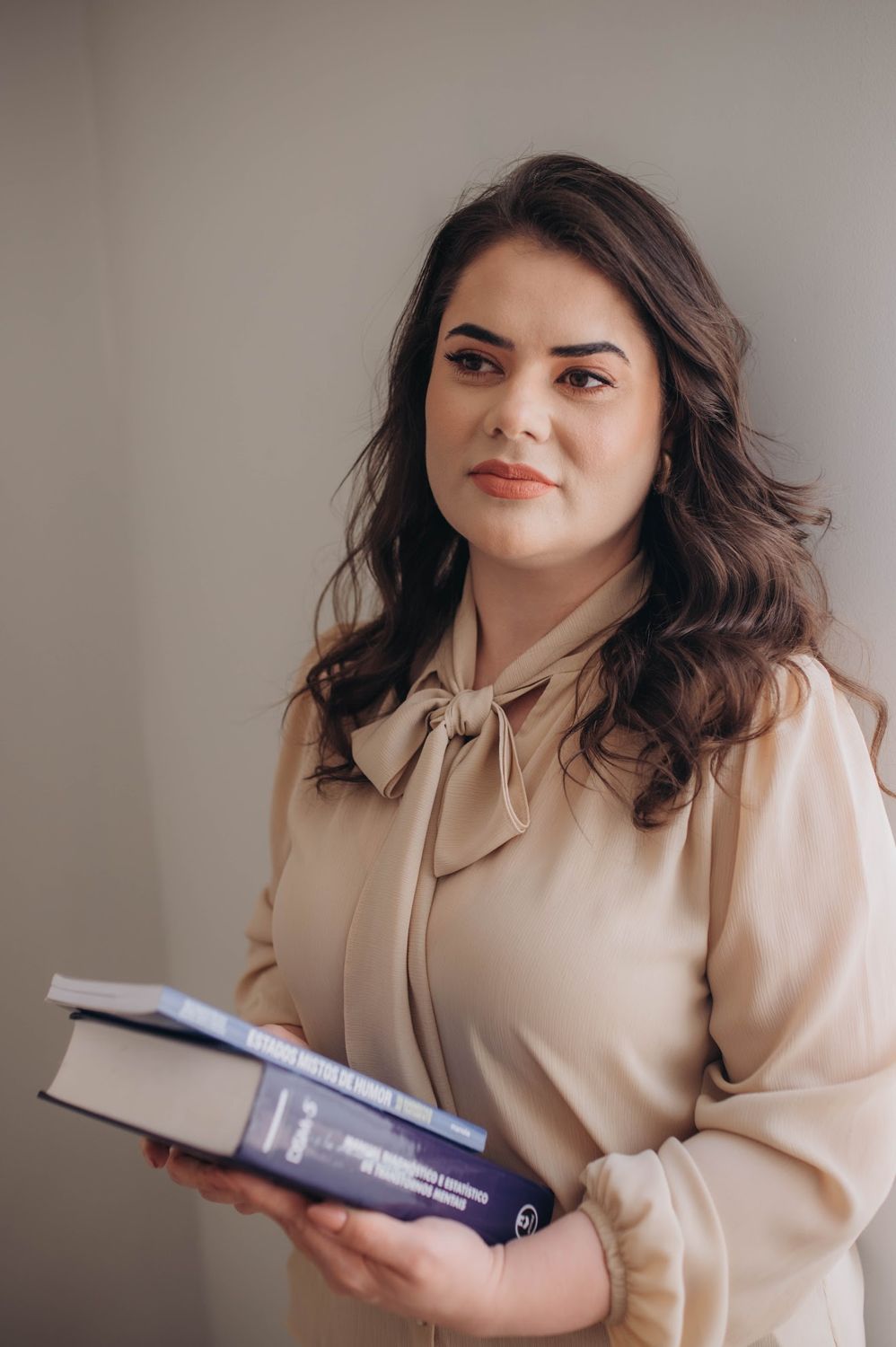 Dra. Karine Homem segurando livros de psiquiatria